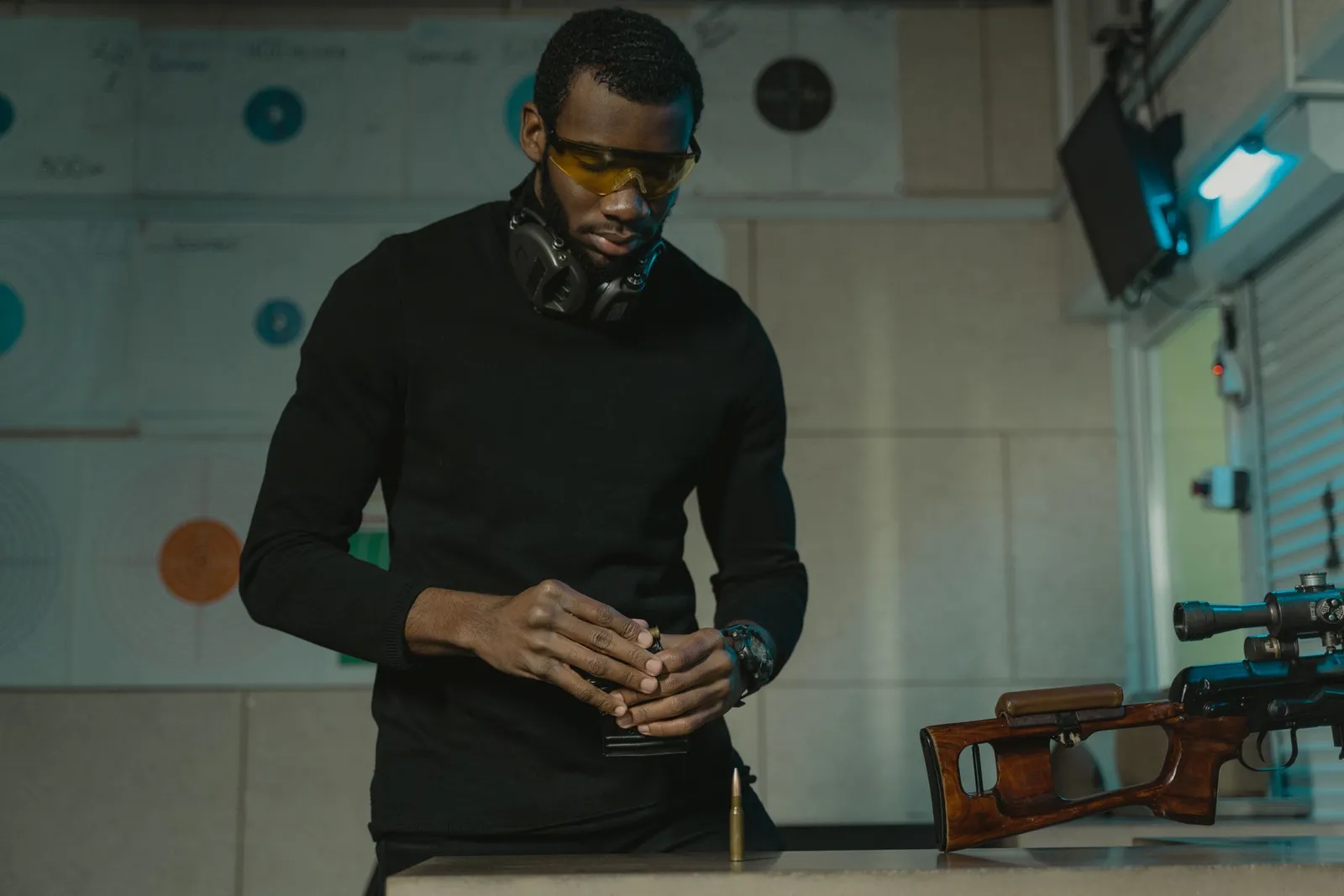 Tireur portant des lunettes de protection préparant son matériel sur une table dans un stand