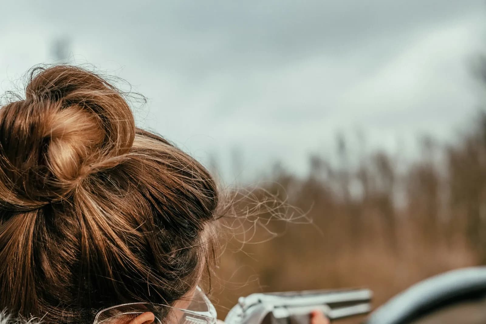 Tireuse vue de dos, concentrée au moment d'épauler sur un pas de tir en extérieur