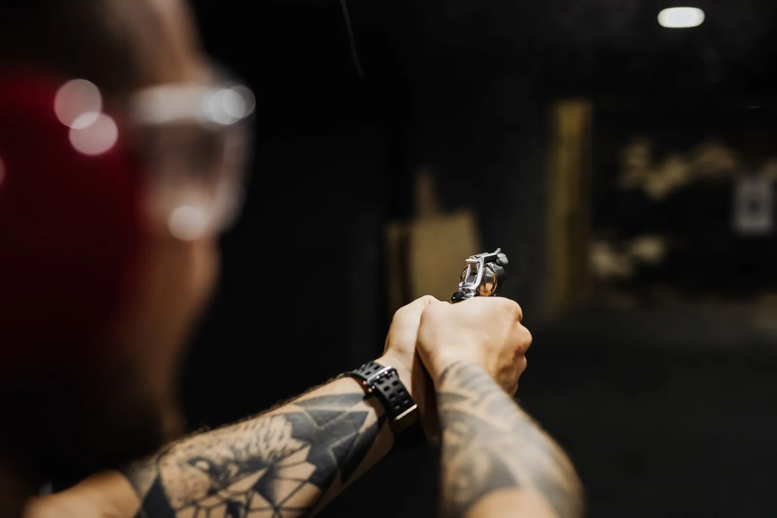 Tireur au pistolet portant des lunettes de protection dans un stand sombre