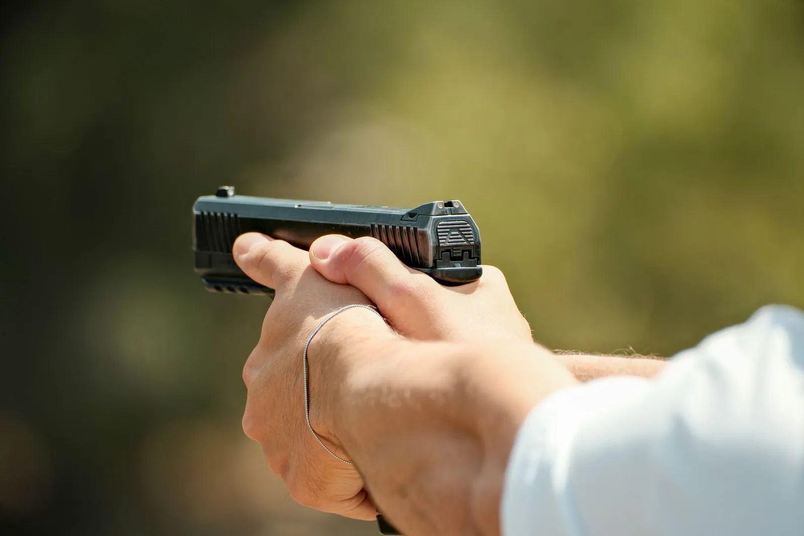 Mains tenant fermement un pistolet en extérieur, vue de près