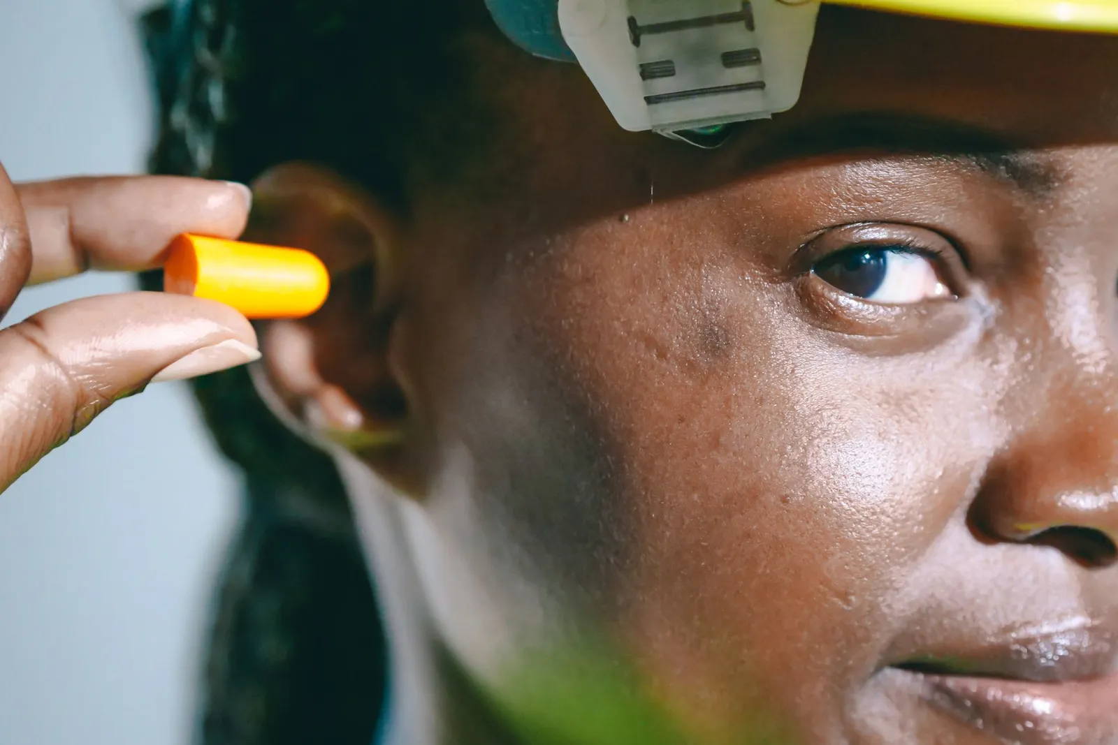 Personne insérant un bouchon d'oreille orange en mousse dans son oreille