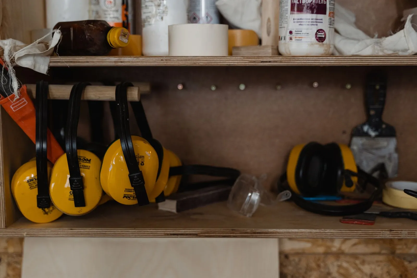 Plusieurs casques antibruit jaunes rangés sur une étagère en bois