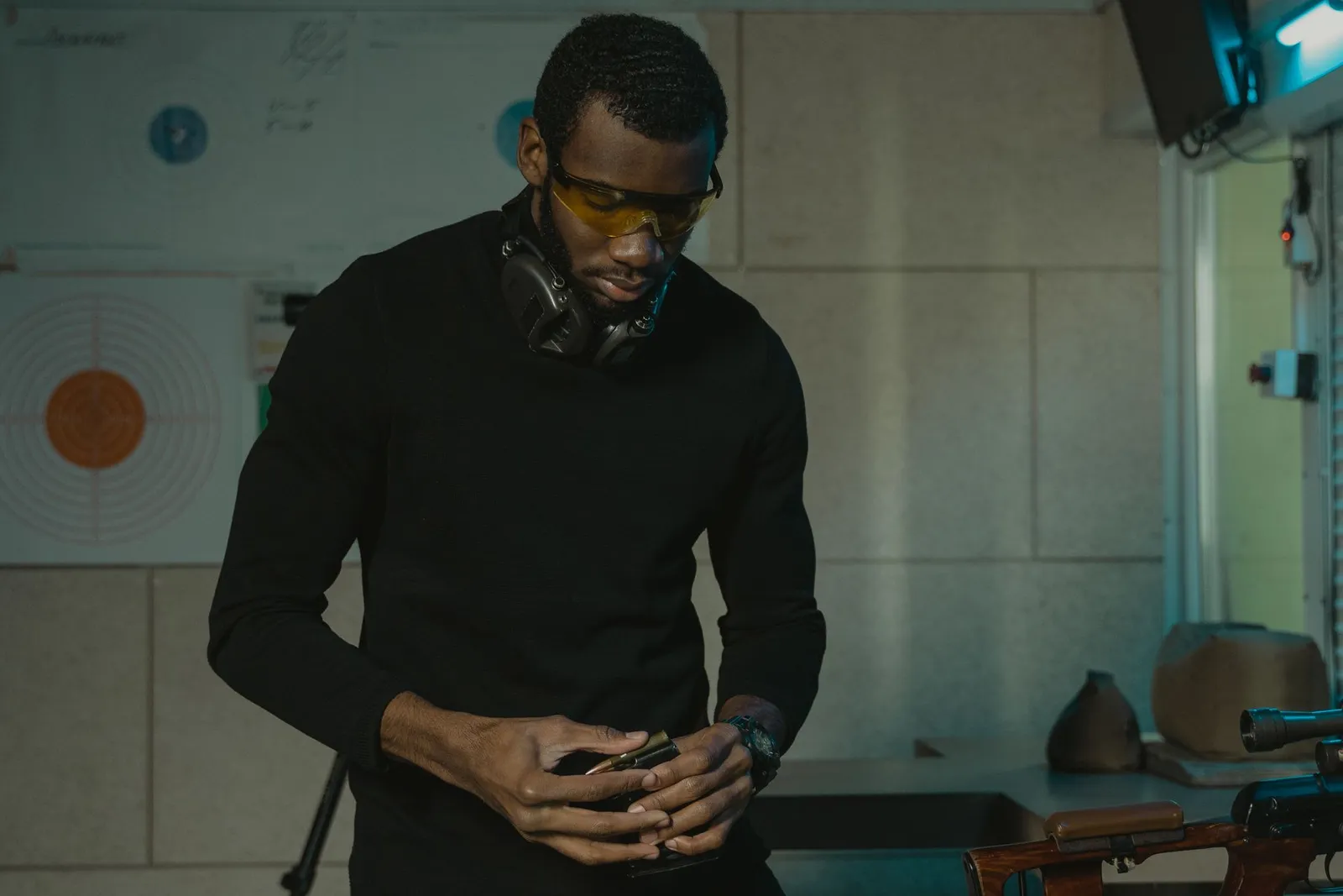 Tireur portant des lunettes de protection et un casque antibruit préparant son matériel au stand