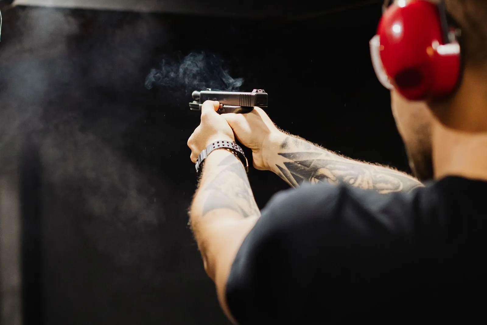 Tireur au pistolet dans un stand intérieur portant un casque antibruit rouge