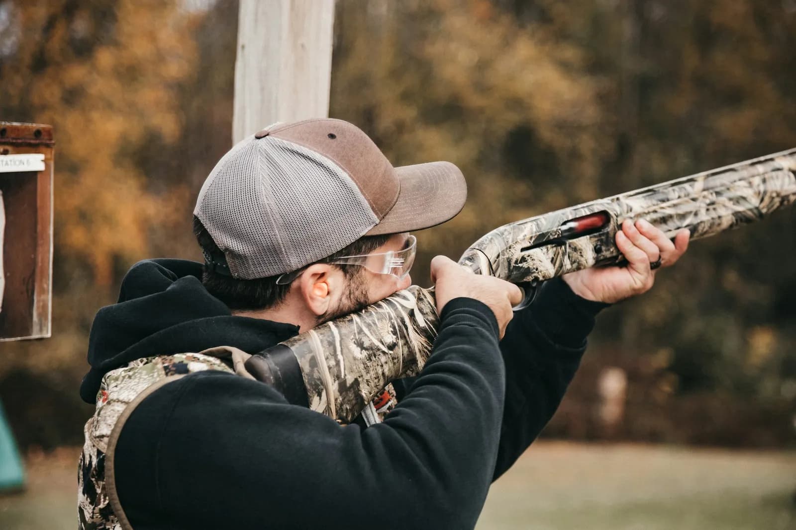Tireur au fusil portant des lunettes de protection et une casquette sur un pas de tir extérieur